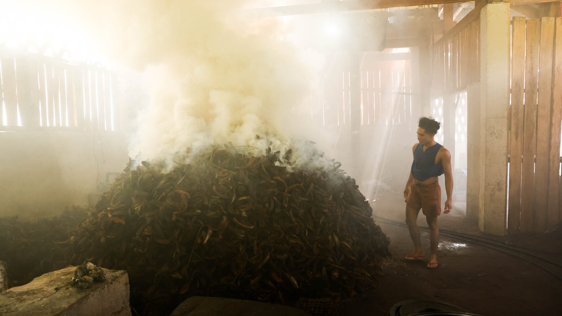 A man watches as coconut husks burn.