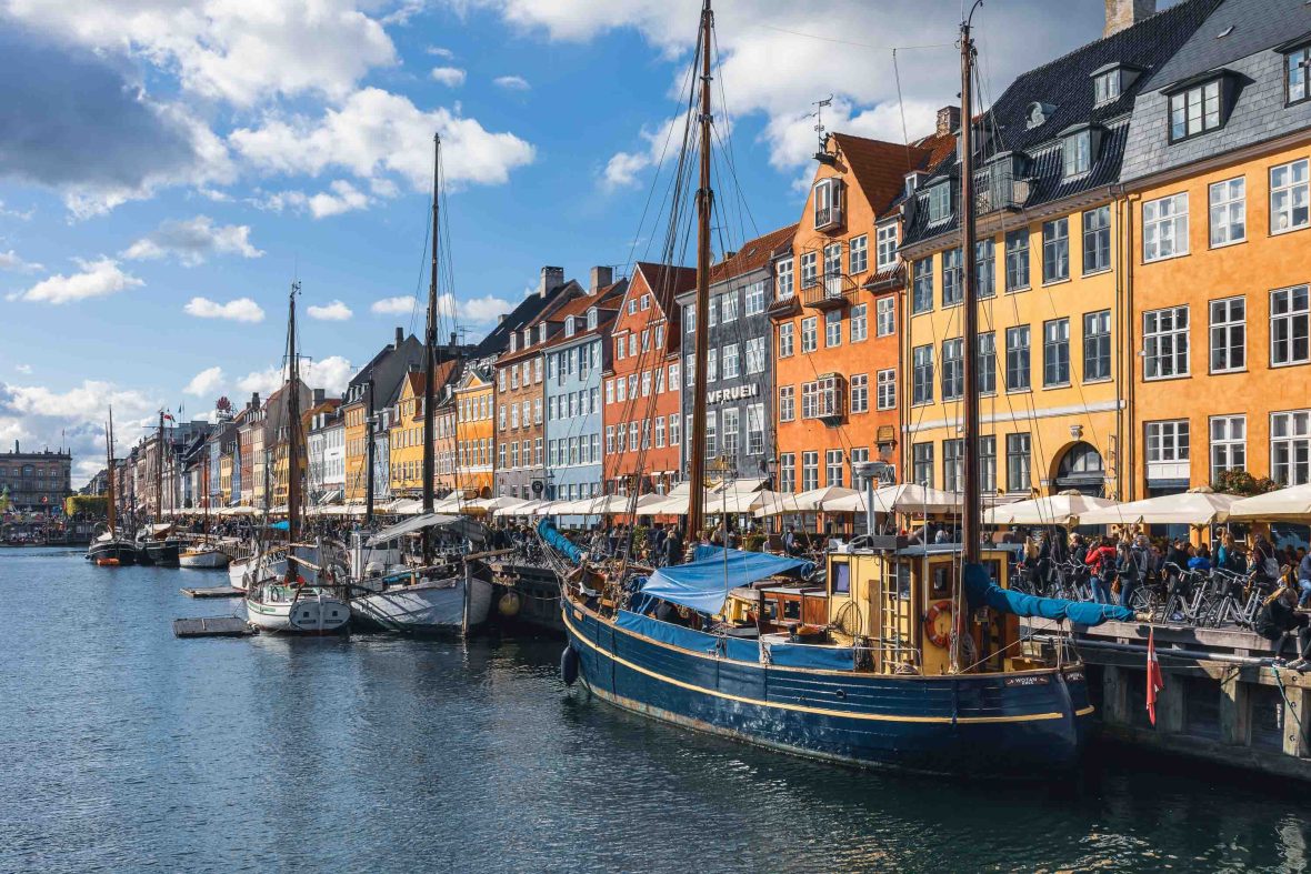 Boats line the canal waterfront against a backdrop of buildings, bars and restaurants