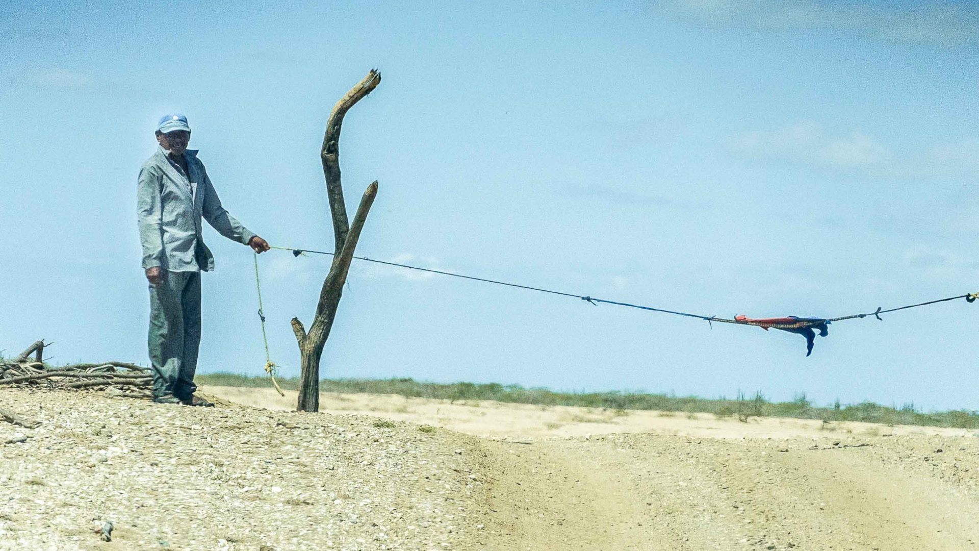 A man holds a flimsy barrier at a checkpoint.