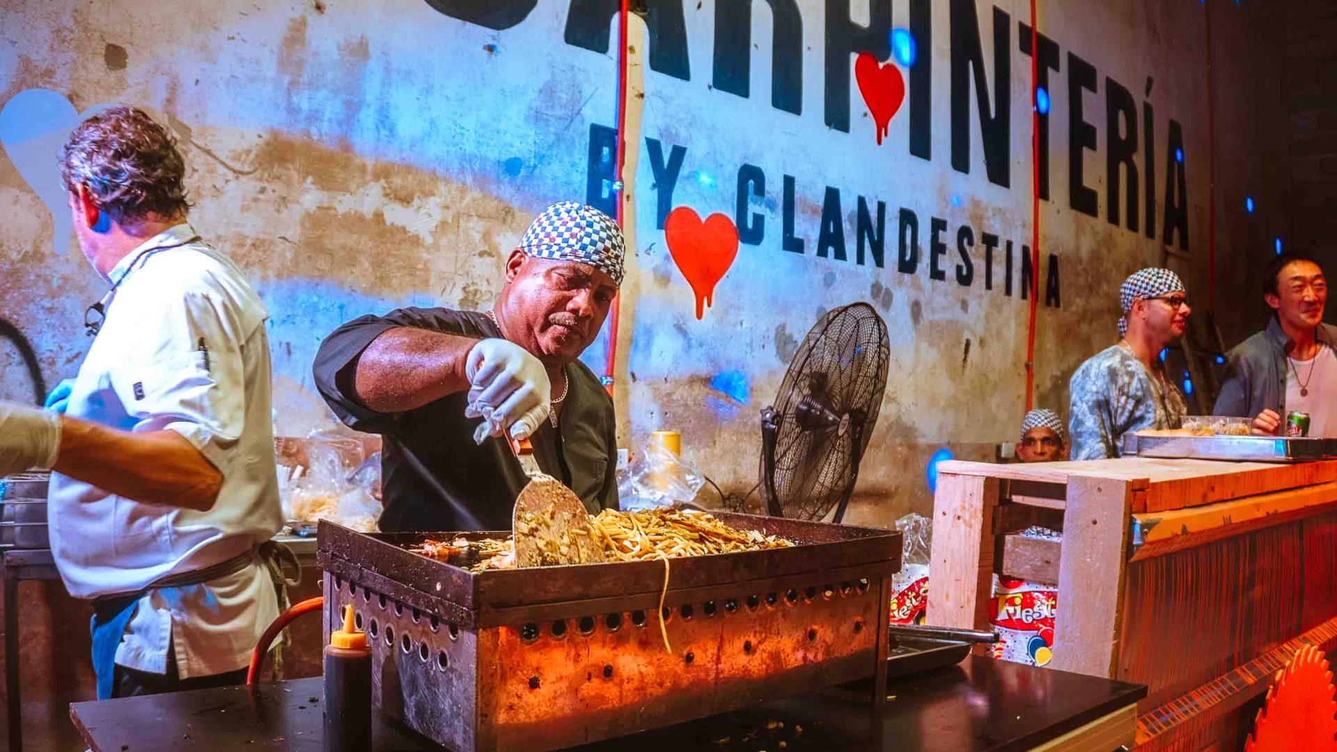 A man cooks food over a grill at an outdoor event.