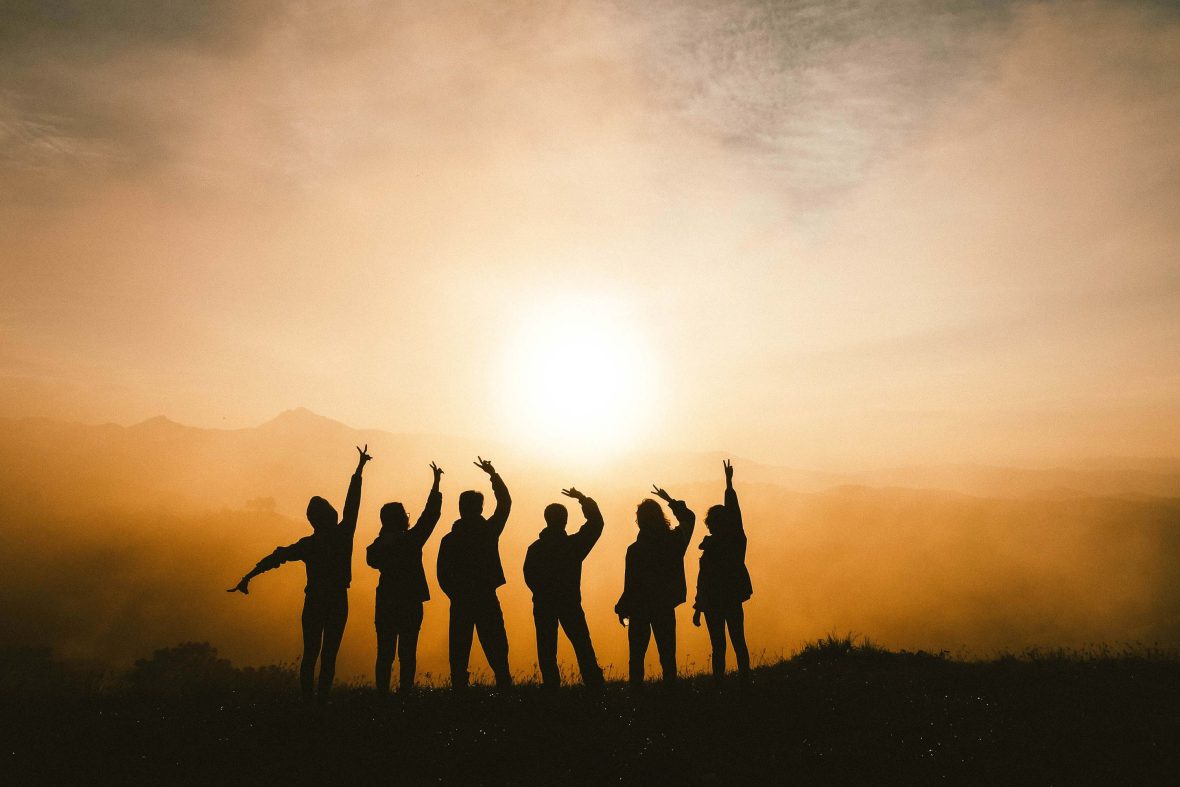 Friends silhouetted against an orange sky.