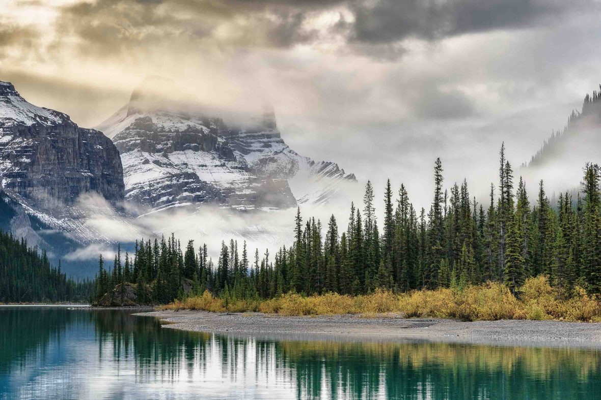 A lake with snowy mountains and trees.