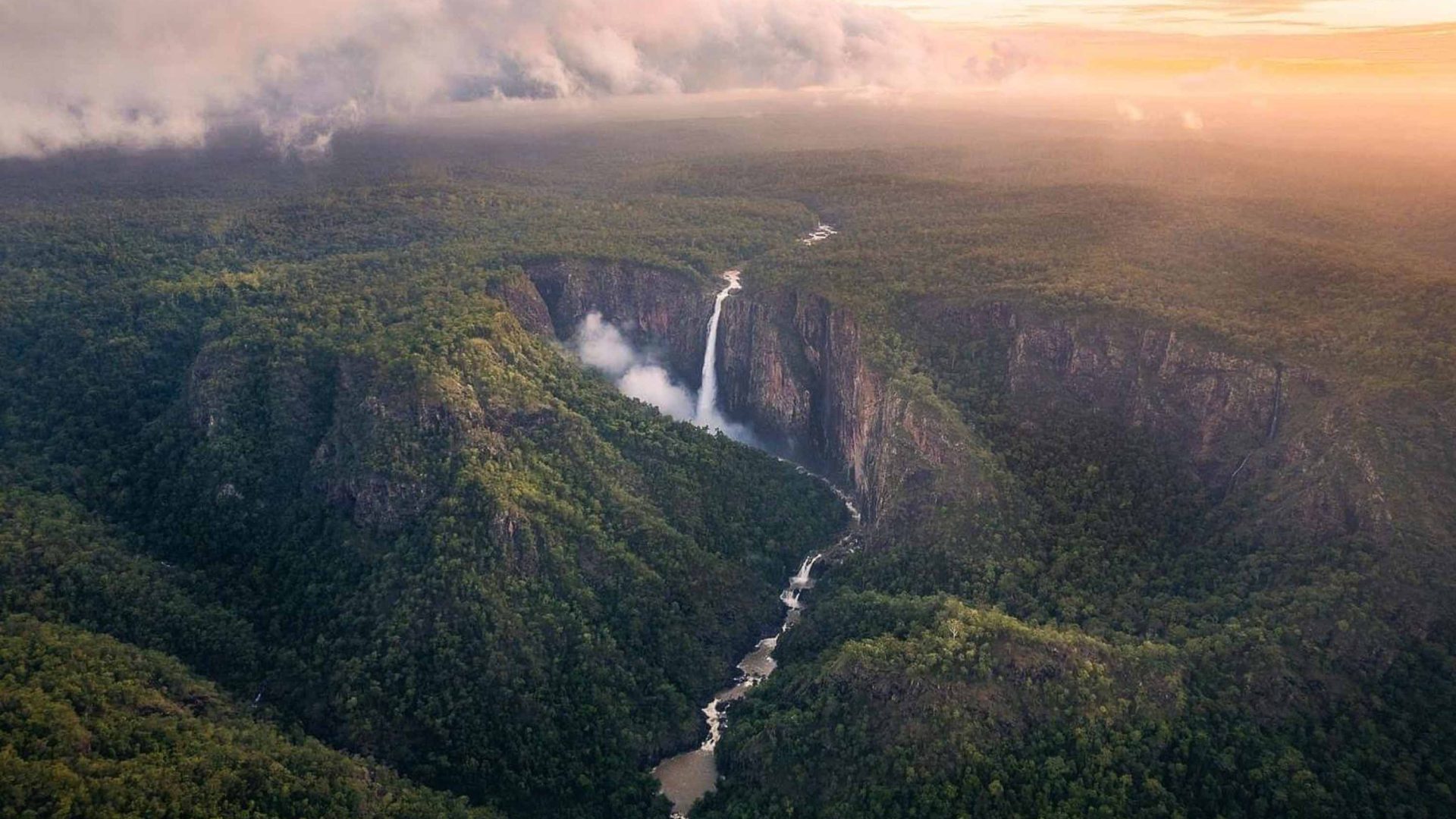 Trees and plateau's surround a waterfall, seen from an aerial view.