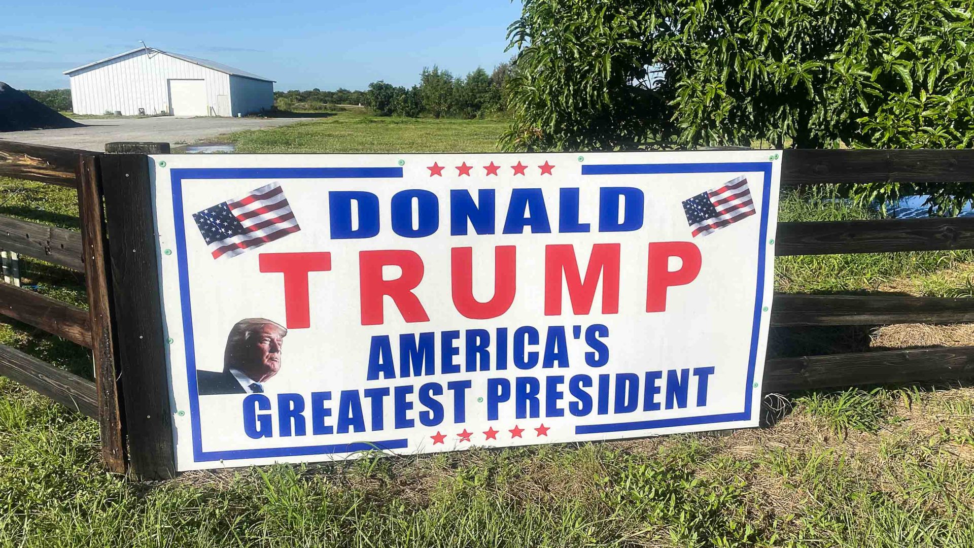 A sign on a fence that reads 'Donald Trump, America's greatest President'