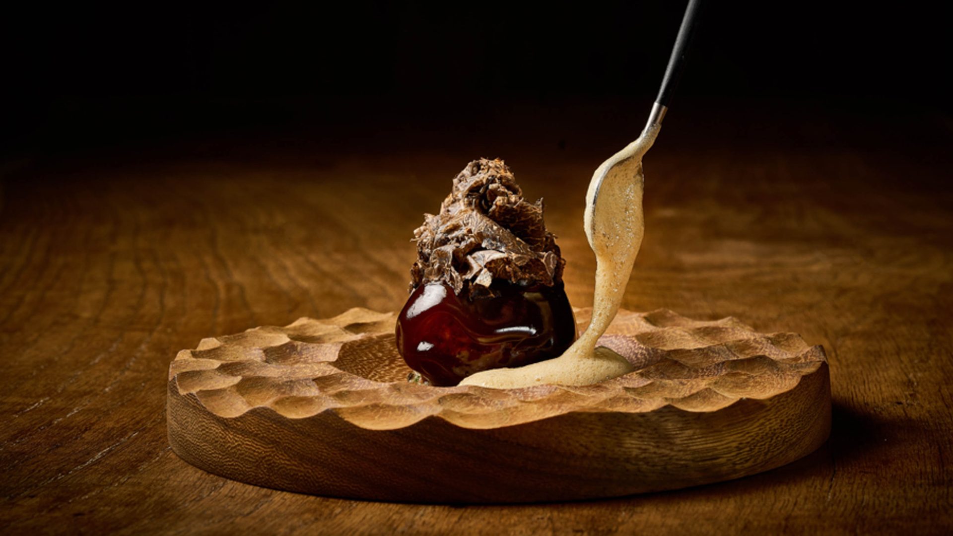 Iberian Pork is served on a brown dish with a spoon.