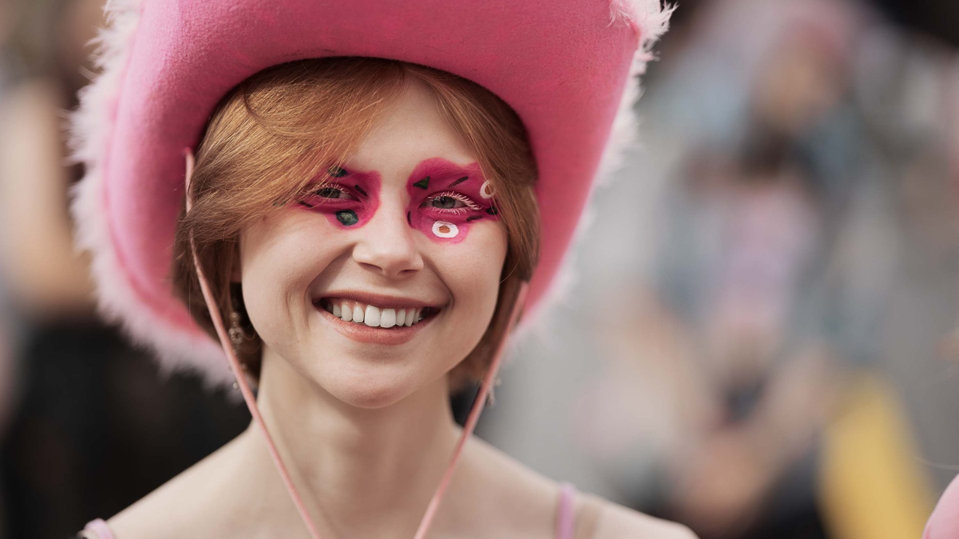 A young woman in a pink cowgirl hat with pink eye make up and a pink top.