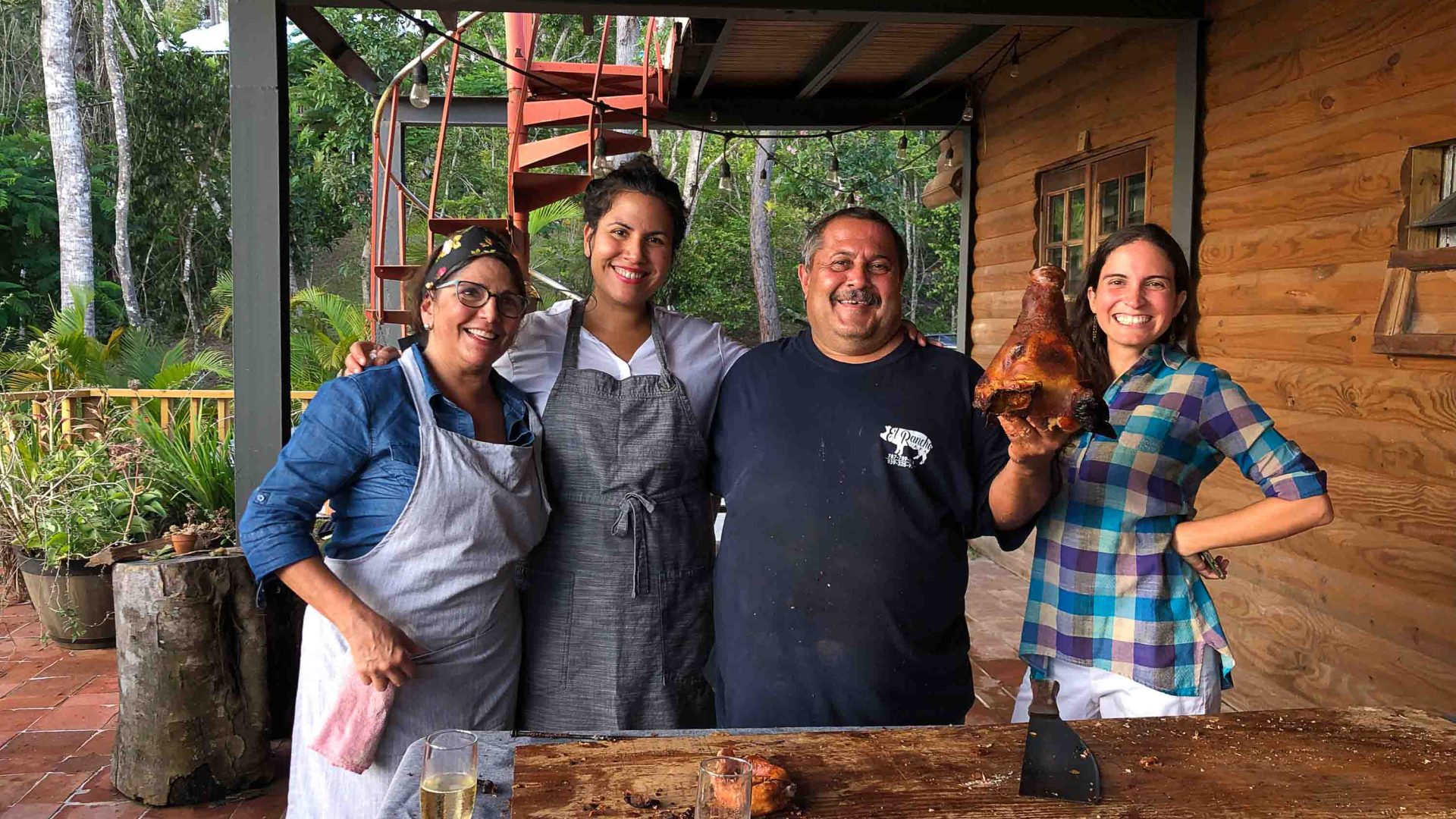 Staff and team at El Pretexto together at a chopping board. They hold up a piece of meat.