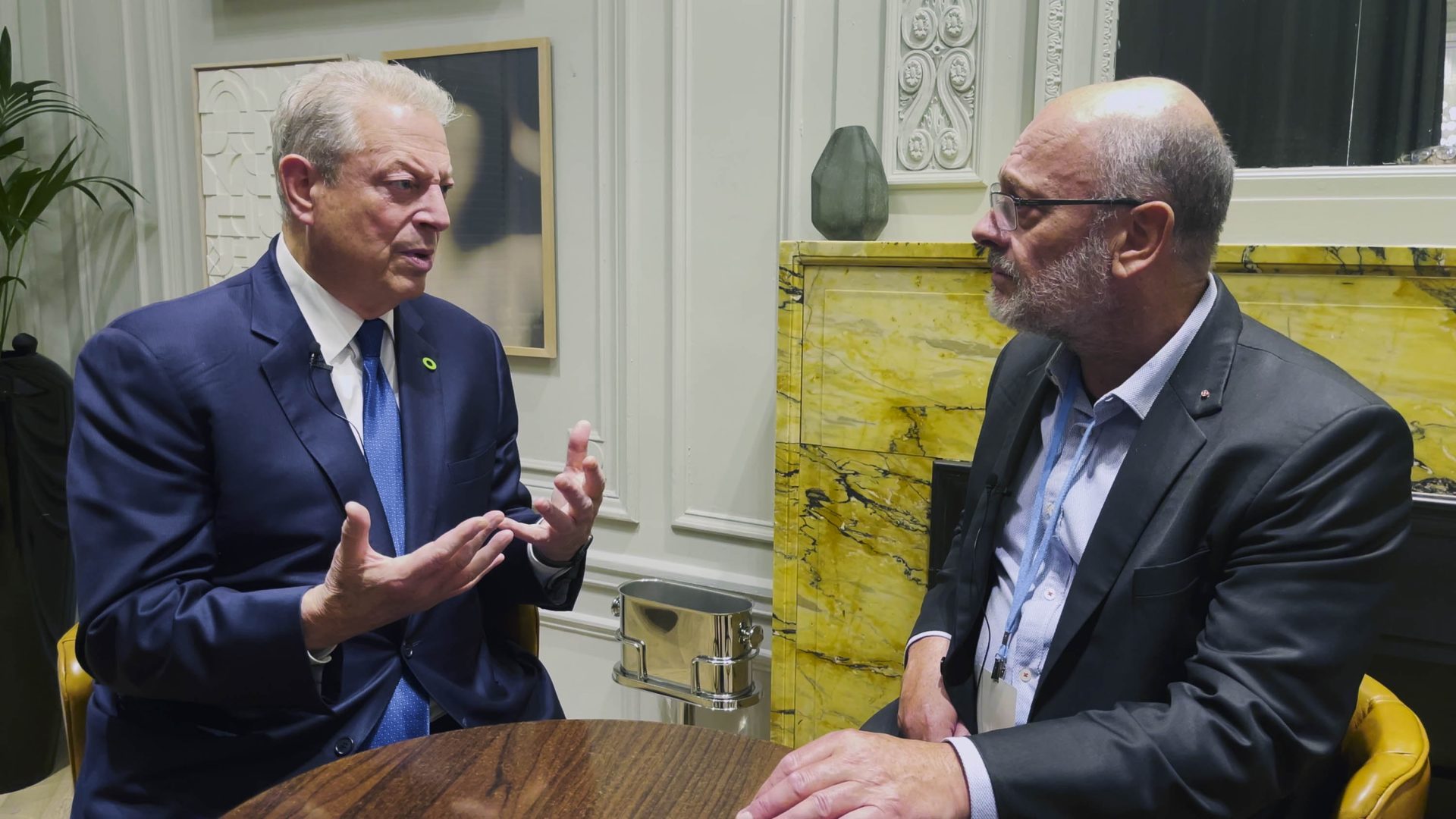 Al Gore talks with Tim Flannery at a table.