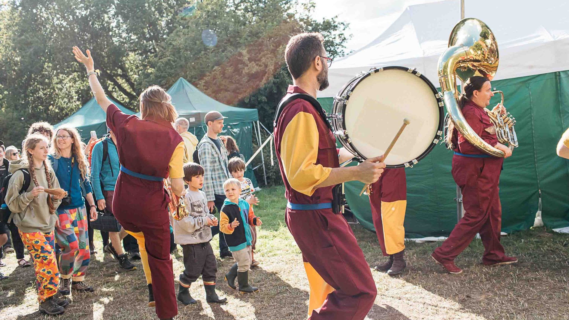 People play instruments and dance in matching maroon and yellow outfits.