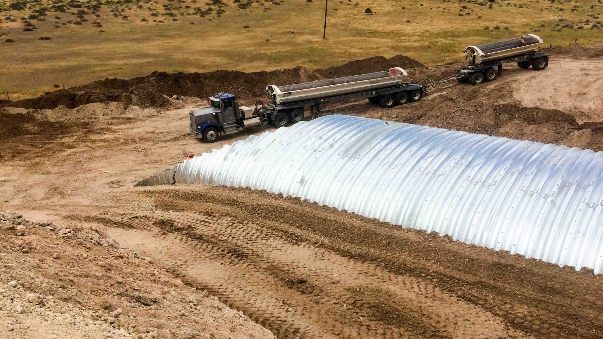 A backfilled wildlife crossing in Utah with a truck working nearby.