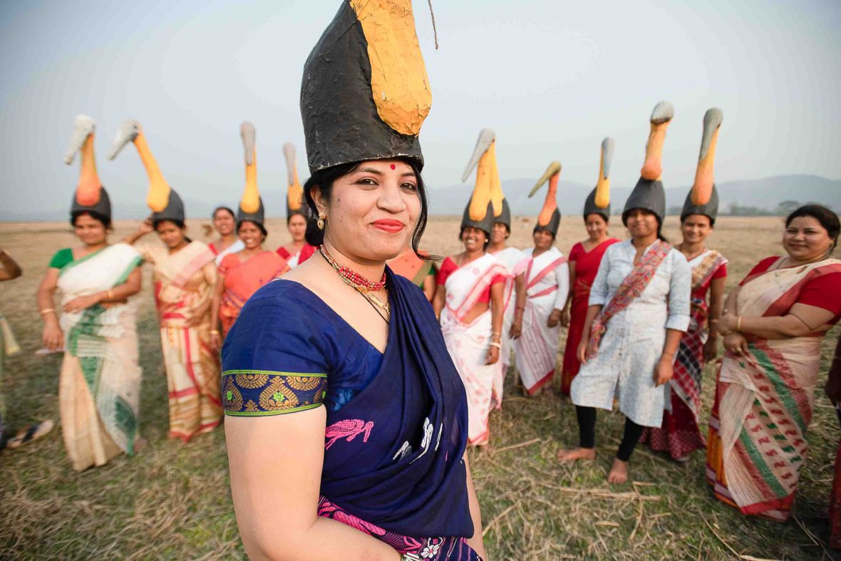 Purnima Devi Barman with some of the women she has engaged in her work with Storks. They wear stork hats and stand in a row behind her.